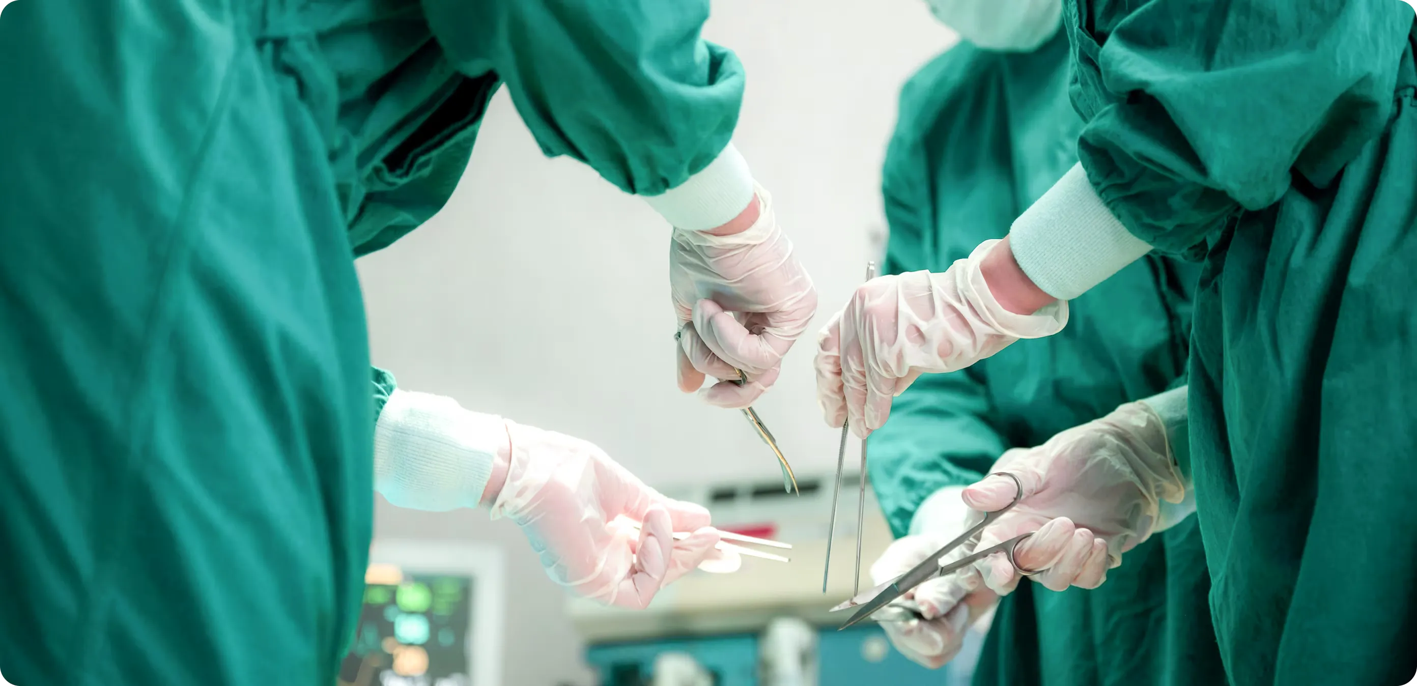 Chirurgisches Team bei einer Operation im OP-Saal, konzentriert arbeitend unter hellem OP-Licht, mit steriler Kleidung und medizinischen Instrumenten.