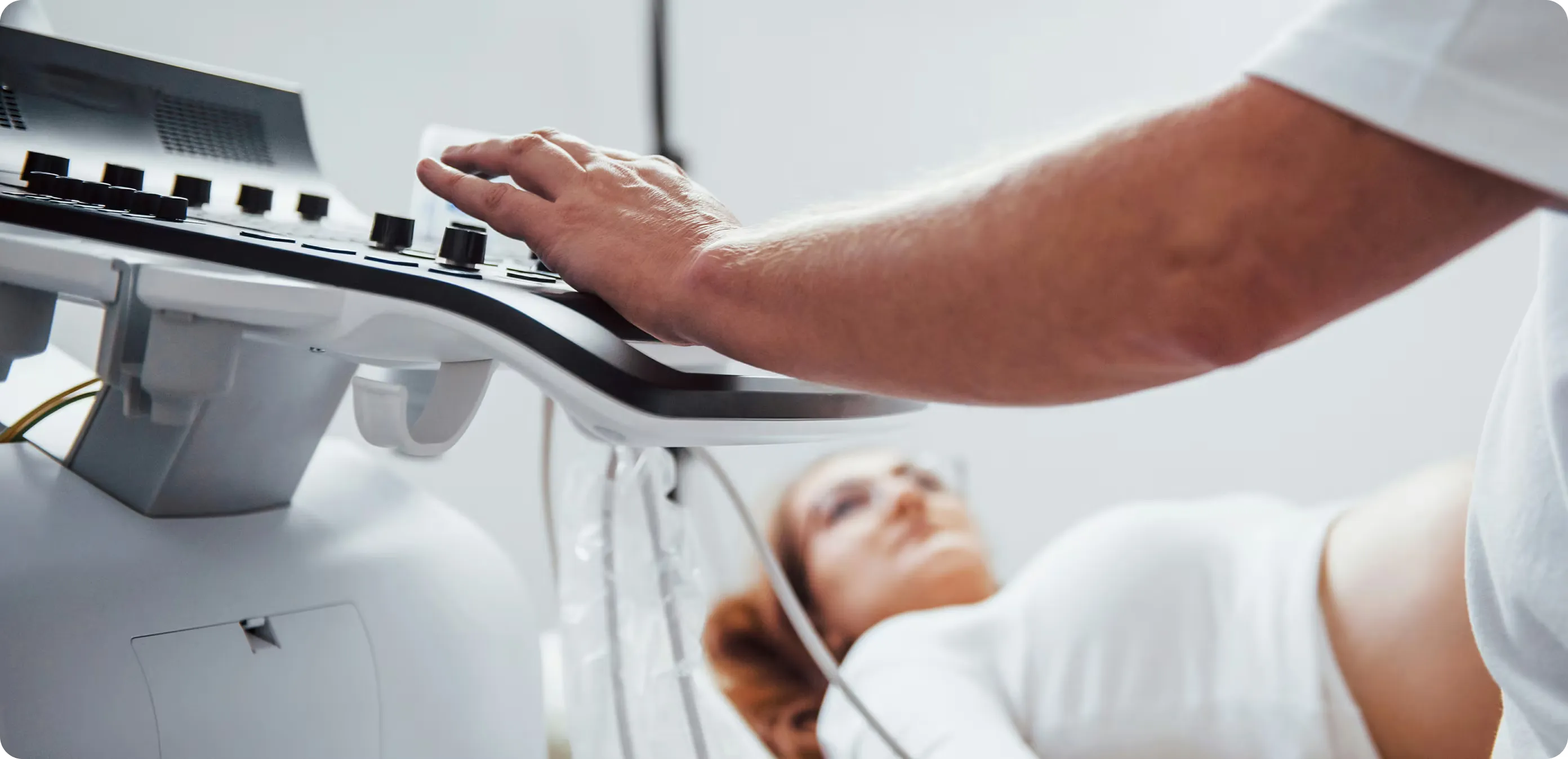 Patientin liegt auf dem Behandlungstisch, Behandler drückt Knopf auf dem Ultraschallgerät